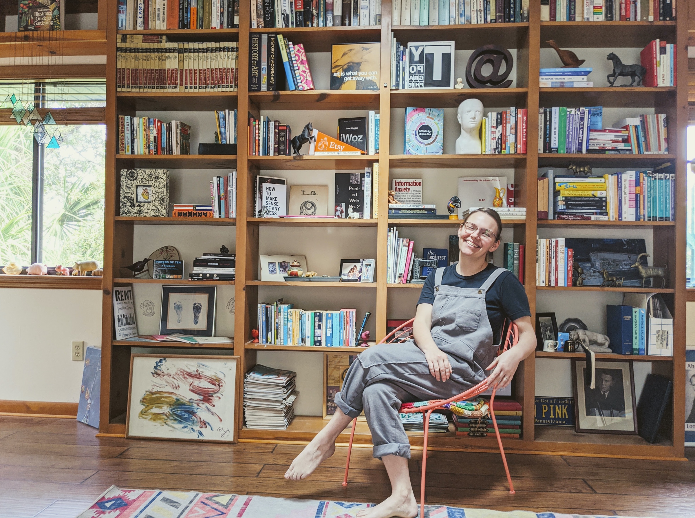 A picture of Abby Covert at home in her studio, amongst her books many of which are about information architecture and design